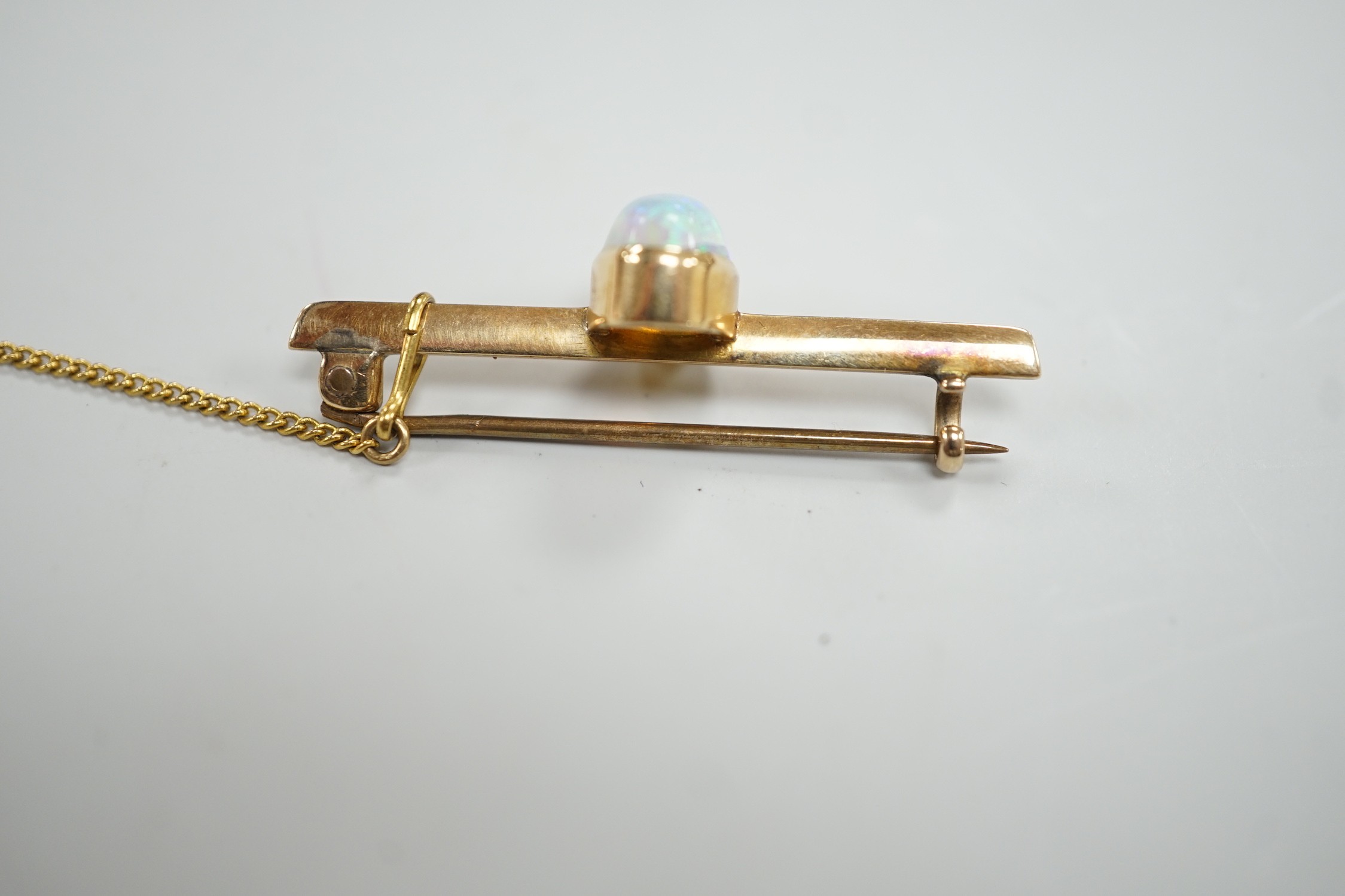A yellow metal and single stone oval white opal set bar brooch, 39mm, gross weight 4.3 grams.